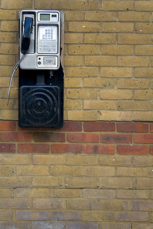 A public telephone against a brick wall.の写真素材