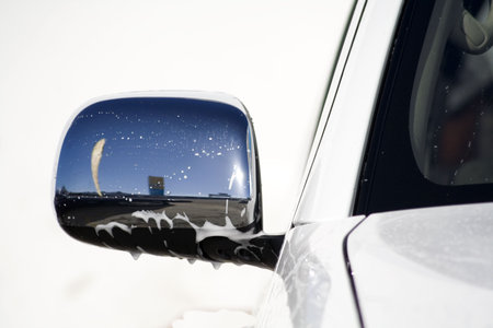A reflection of the blue sky and a flag in chrome rear-view mirror of a car.  の写真素材