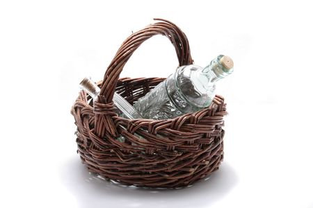 One old brown wicker basket with two clear empty bottles on a white background. の写真素材