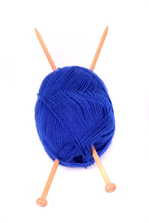 A ball of blue wool with two wooden knitting needles on a white background. 