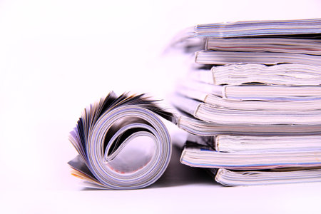 A stack of magazines with one rolled up on a white background. 