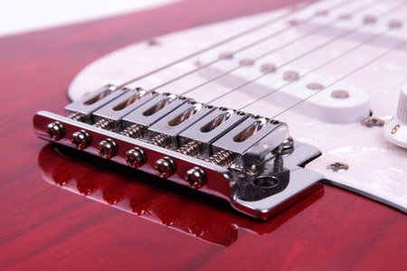 Close-up of the strings of a red electric guitar.