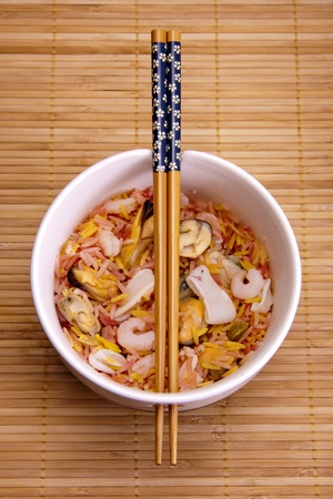 Fragrant rice and seafood in a bowl with chopsticks, ready to be eaten. の写真素材