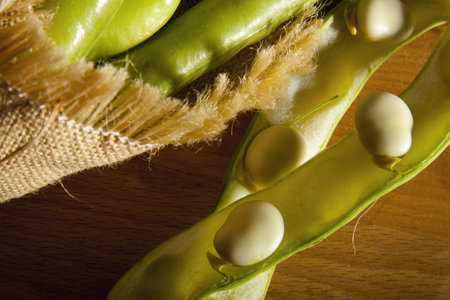 Fresh broad beans in Hessian bag on a market stall. 