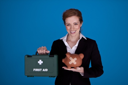 Young attractive businesswoman holding a piggybank and first aid kit as a money recovery concept. の写真素材