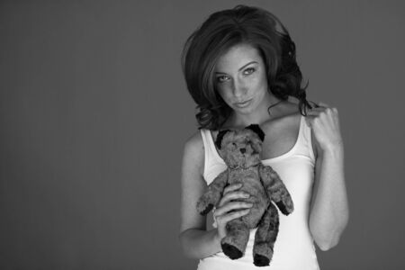 Beautiful young woman holding her small toy bear の写真素材