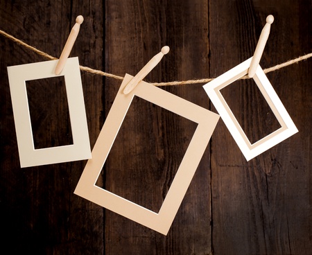Close up of three photo frames and clothes pegs on a rope over a wooden background の写真素材