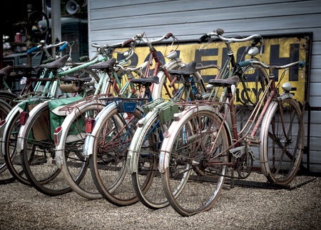 A group of old rusty retro pushbikes parked in a row のeditorial素材