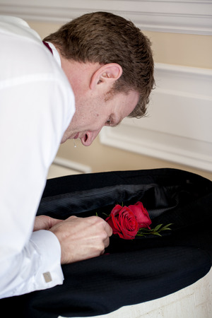 A handsome groom is trying his best to fit his rose to his jacket の写真素材