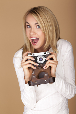 Female photographer holding a vintage camera over a brown background.の写真素材