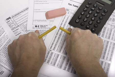 Hands breaking pencil in frustration over tax forms