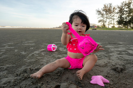 Portrait of cute asian girl playing sand during summer time on the beach.の写真素材