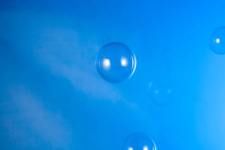 Transparent air soap foam bubble isolated on blue background
