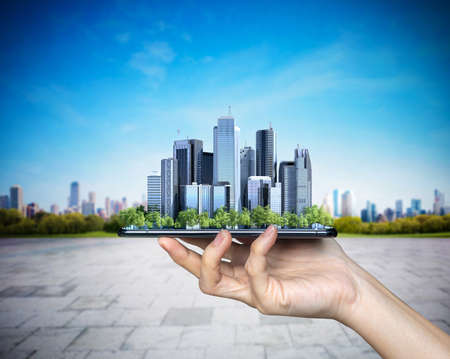 Businessman hand lifting smart city with mobile phone.の写真素材