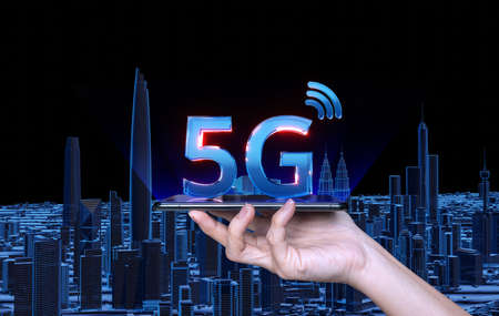 Hand holding smart phone with a 5G 3D icon on the background of the kuala Lumpur city. The concept of 5G network, high-speed mobile Internet.の写真素材