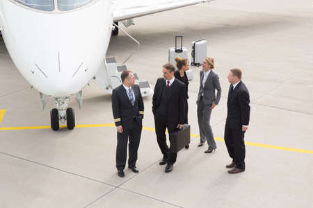 executive business team in front of corporate jet pilot talking toの写真素材