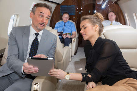 business team traveling in corporate jet and discussing a presentationの写真素材