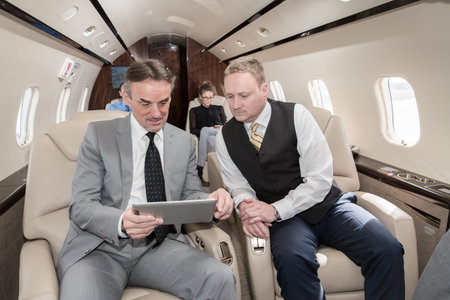 business team traveling in corporate jet and discussing a presentation