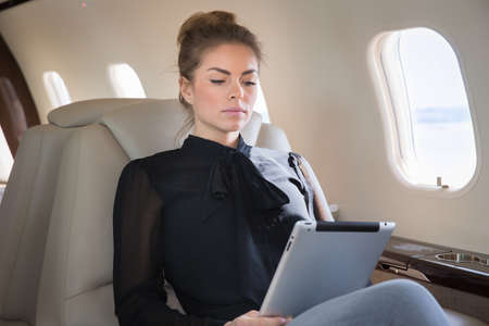 woman in corporate jet looging at tablet computerの写真素材