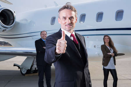 thumbs up business team in front of corporate private jetの写真素材