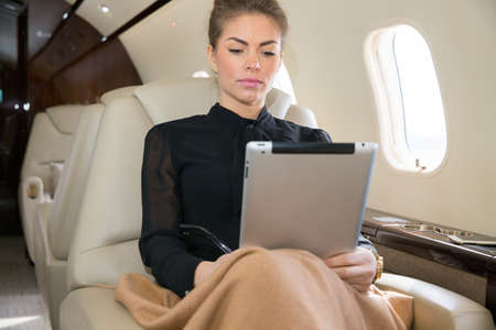 woman in corporate jet looking at tablet computerの写真素材
