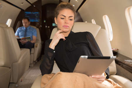 woman in corporate jet looking at tablet computerの写真素材