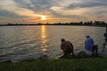 Two men filling their pails from the reservoirの写真素材