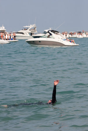 Chicago, IL, USA - May 26, 2012   A lone male swimmer in wetsuit swims the backstroke amid party boats in Lake Michigan のeditorial素材