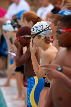 Lawrenceville, GA, USA - June 14:  Male junior swimmers prepare to swim their legs of a relay race during a neighborhood swim meet between three swim teams.のeditorial素材