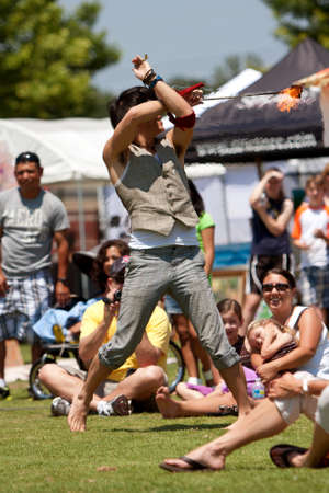 Suwanee, GA, USA - May 19, 2012:  A male circus performer entertains the crowd while slinging balls of fire while performing at Arts In The Park, a spring festival held at Suwanee Town Park.  The perfomer represents The Imperial OPA Circus, a local troupeのeditorial素材