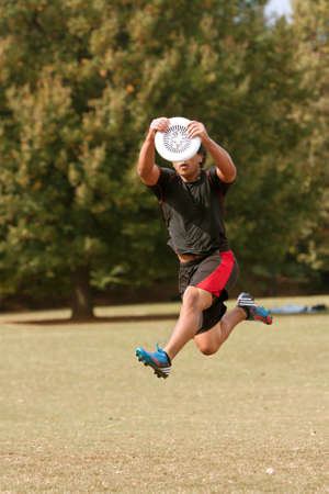 Atlanta, GA USA - October 27, 2012:  An unidentified young male jumps to catch a frisbee during an Ultimate Frisbee game between two teams in Piedmont Park.のeditorial素材