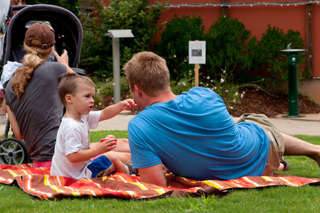Roswell, GA, USA - July 13, 2013:  A little boy feeds ice cream to his father laying on a picnic blanket, at the Chattahoochee Nature Center's Butterfly Festival. のeditorial素材