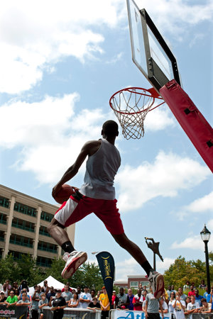 Athens, GA, USA - August 24, 2013:  A young man jumps high attempting a reverse dunk in the slam...