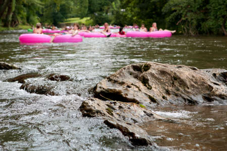 A Group Of Defocused People Tubing Down RiverApproach Boulder In Focusのeditorial素材