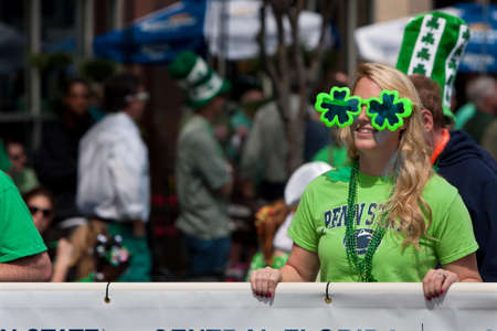 Atlanta, GA, USA - March 15, 2014   A woman wearing shamrock sunglasses carrries a banner down Peachtree Street as part of the St  Patrick s paradeのeditorial素材