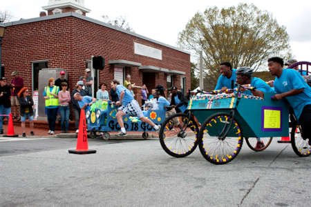 Lawrenceville, GA, USA - March 29, 2014:  Two teams push silly looking beds around a downtown street corner in the annual Lawrenceville Bed Race, to benefit a local Gwinnett County homeless shelter.のeditorial素材