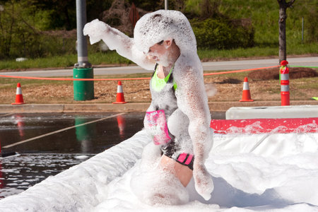 Atlanta, GA USA - April 5, 2014   A young woman emerges from the foam pit covered head to toe in bubbles, at   the Ridiculous Obstacle Challenge  ROC  5k race のeditorial素材