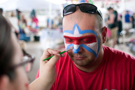 McDonough, GA, USA - May 10, 2014:  A man gets a Lafleur symbol painted on his face at the annual Dog Days of McDonough festival.のeditorial素材