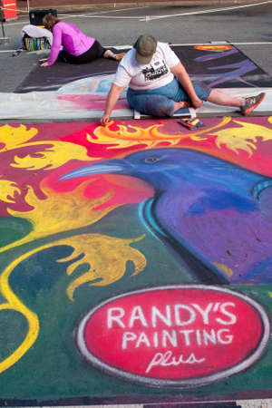 Marietta, GA, USA - October 11, 2014:  A chalk artist sits on the pavement to draw an elaborate Halloween scene on a downtown street as part of the Marietta Chalkfest.のeditorial素材