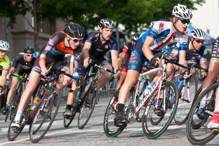 Athens, GA, USA - April 25, 2015:  A tightly packed group of male cyclists lean into a turn while racing in an amateur race on the streets of downtown Athens, in the annual Twilight Criterium.のeditorial素材