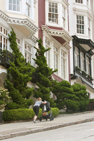 San Francisco, CA, USA - May 18, 2015:  A woman struggles to push a baby stroller up a very steep incline in the Nob Hill area of San Francisco.のeditorial素材