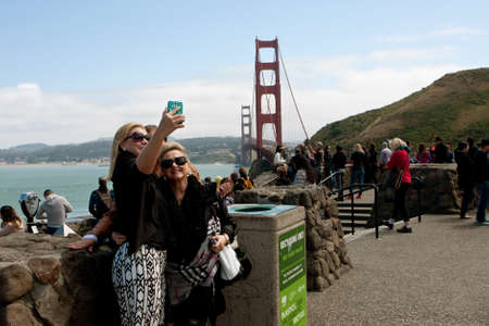 San Francisco, CA, USA - May 15, 2015:  Three women take a selfie with a smart phone, with the Golden Gate Bridge in the background, in San Francisco.のeditorial素材