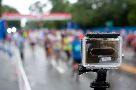 Atlanta, GA, USA - July 4, 2015:  A GoPro camera mounted on a tripod shoots time-lapse photography of runners crossing the finish line in the rain at the annual Peachtree Road Race 10K in Atlanta.のeditorial素材