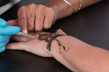 Atlanta, GA, USA - September 12, 2015:  An artist skillfully designs a henna temporary tattoo on a woman's hand at the 5 Arts Fest in Atlanta.のeditorial素材