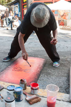 Atlanta, GA, USA - September 12, 2015:  An artist flicks red paint onto the painting he's creating on the pavement at the 5 Arts Fest in Atlanta.のeditorial素材