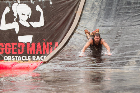 Conyers, GA, USA - August 22, 2015:  A man goes down a giant water slide headfirst into a pool of...