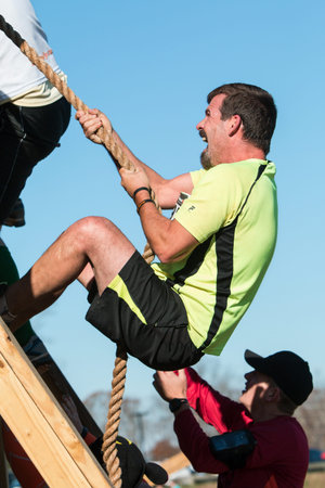 Buford, GA, USA - November 21, 2015:  A man struggles to use a rope to climb up a wall at one of the...