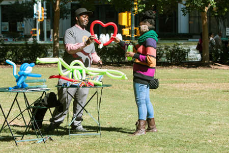 Atlanta, GA, USA - October 17, 2015:  A balloon animal maker hands a female customer a heart-shaped balloon at the Elevate Art festival in Woodruff Park on October 17, 2015 in Atlanta, GA.のeditorial素材