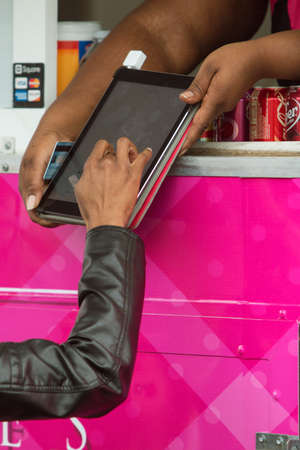 Marietta, GA, USA - March 26, 2016:  A woman signs a digital tablet with her finger in a food truck credit card transaction at an event on March 26, 2016 in Marietta, GA.のeditorial素材