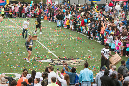 Marietta, GA, USA - March 26, 2016:  Teen volunteers cover a high school football field with plastic easter eggs and candy, as hundreds of local residents wait to begin a massive community easter egg hunt at Sprayberry High School on March 26, 2016 in Marのeditorial素材